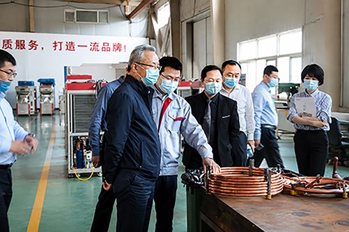 Government representatives communicating with SCICOOLING engineers beside environmental test equipment.
