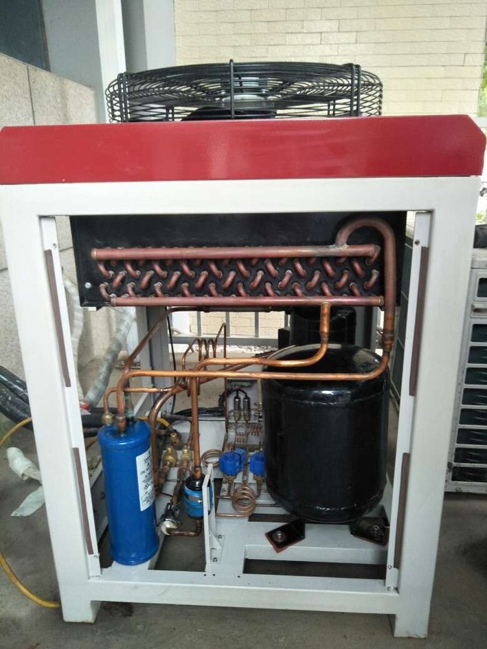 Internal components of an environmental test equipment unit after maintenance, showing a clean compressor and piping system.