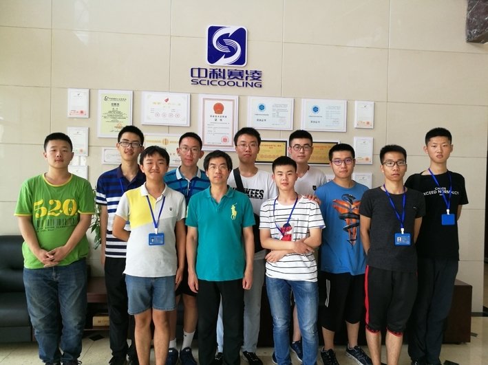 A group of Beihang University students and SCICOOLING staff posing for a photo in front of the company logo.