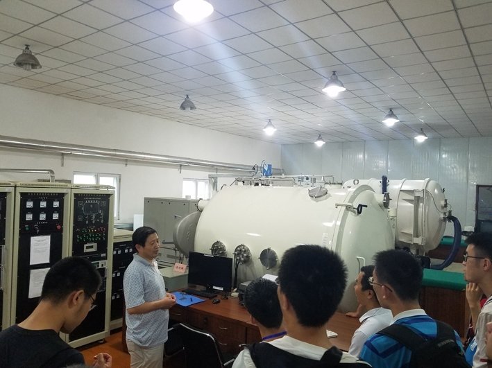 Visitors observing a large environmental simulation testing chamber inside a laboratory.