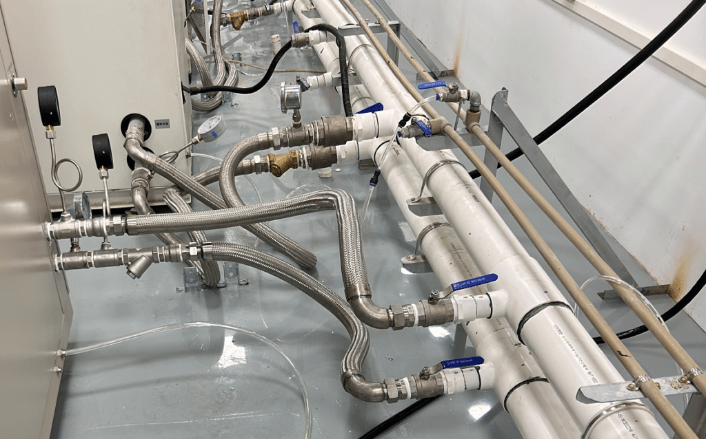 Stainless cooling-water pipes, hoses and valves inside a test chamber system
