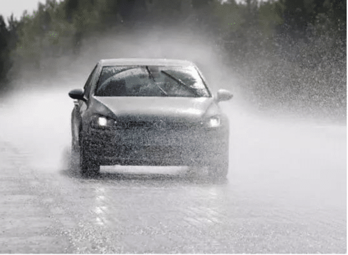 Passenger car driving through heavy rain to illustrate water exposure testing