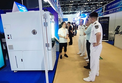 Exhibition staff demonstrating a large environmental chamber to visitors