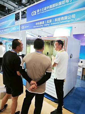 Visitors inspecting the interior of an environmental chamber at the booth